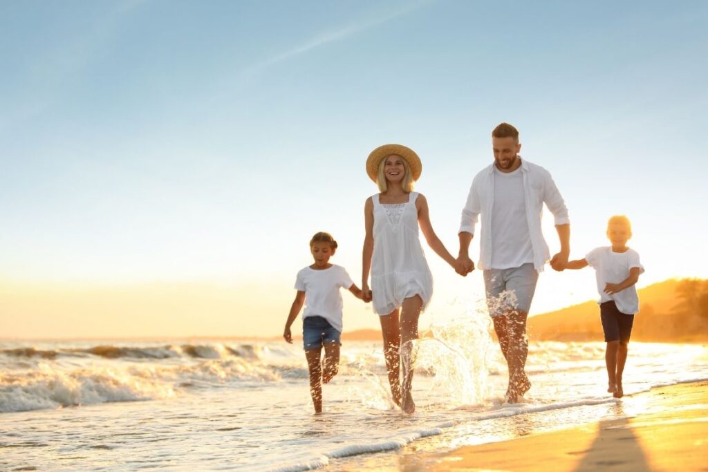 Family walking on beach at sunset